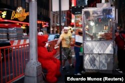 Jorge, seorang imigran dari Meksiko, berpakaian sebagai karakter Sesame Street Elmo, menukar tipnya dengan uang kertas yang lebih besar dari penjual mobil makanan jalanan di Times Square, New York, 30 Juli 2014. (Foto: REUTERS/Eduardo Munoz)