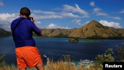 Seorang turis asing mengambil gambar di atas puncak Pulau Kelor di Taman Nasional Komodo, NTT, pada 23 Agustus 2016. (Foto: Reuters/Beawiharta)