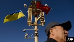 FILE - A man passes under a lamp post displaying Ukrainian and Chinese flags on Tiananmen Square in Beijing, China, Dec. 5, 2013. While Ukrainian President Volodymyr Zelenskyy has said that China has shown “neutrality” in his country's conflict with Russia, others beg to differ.