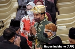 Presiden Joko Widodo (tengah) menyapa anggota parlemen sebelum menyampaikan pidato tahunannya di parlemen di Jakarta pada 16 Agustus 2022, menjelang perayaan Hari Kemerdekaan. (Foto: AFP/BAGUS INDAHONO)