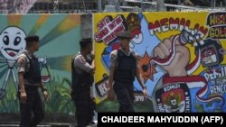 Polisi berjalan di depan mural kampanye Pemilu 2019 di Banda Aceh, 17 Maret 2019. (Foto: AFP/CHAIDEER MAHYUDDIN)