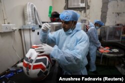 Seorang karyawan Shellios Technolabs, yang memproduksi helm sepeda motor yang dilengkapi dengan filter dan kipas di bagian belakang helm, sedang merakit helm di New Delhi, India, 23 Agustus. 2022. (Foto: REUTERS/Anushree Fadnavis)