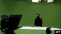 Masheed Barzz, seorang presenter untuk stasiun televisi 1TV, tambil dengan penutup wajah saat melakukan siaran di Kabul, Afghanistan, pada 25 Mei 2022. (Foto: AFP/Wakil Kohsar)