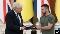Presiden Ukraina Colodymyr Zelenskyy (kanan) memberikan penghargaan kepada Perdana Menteri Inggris pada saat itu, Boris Johnson, dalam kunjungan Johnson ke Kyiv, Ukraina, pada 24 Agustus 2022. (Foto: AP/Andrew Kravchenko)