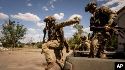 FILE - Ukrainian servicemen of "Fireflies" reconnaissance team jump from the trunk of pickup to take their position at the frontline in Mykolaiv region, Ukraine, Aug. 8, 2022.