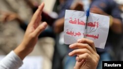 Seorang jurnalis memegang kertas bertuliskan "Jurnalisme bukanlah kejahatan" dalam aksi protes menentang pembatasan terhadap media dan menuntut jurnalis yang dipenjara di Kairo, Mesir, pada 4 Mei 2016. (Foto: Reuters)