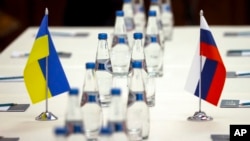 Ukrainian and Russian national flags are placed on the table ahead of peace talks between Russian and Ukrainian delegations in a guest house in the Gomel region, Feb. 28, 2022.