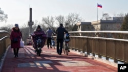 រូបឯកសារ៖ ប្រជាជន​ដើរ​កាត់​ស្ពាន​មួយ​នៅ​ក្បែរ​ស្ថានទូ​ត​រុស្ស៊ី​ក្នុង​ទីក្រុង​ប៉េកាំង ប្រទេស​ចិន ថ្ងៃទី២៤ ខែកុម្ភៈ ឆ្នាំ២០២២។