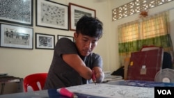 វិចិត្រករ​ ម៉ន ជា​ កំពុង​ឆ្លាក់​រូប​នៅ​លើ​ផ្ទាំង​ប្លុក​ នៅ​ក្នុងបន្ទប់​ស្ទូឌីយ៉ូរបស់​លោក​នៅខេត្តសៀមរាប នៅ​ថ្ងៃទី​ ១២ ខែកុម្ភៈ ឆ្នាំ​២០២២។ (ខាន់ សុគុំមនោ​/វីអូអេ) 