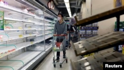 一名香港居民在一家超市空荡荡的货架前走过。（2022年2月28日）