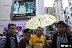 Aktivis pro-demokrasi Tam Tak-chi, tengah, dikawal polisi setelah menghadapi pendukung pemerintah di Hong Kong. (Foto: Reuters)