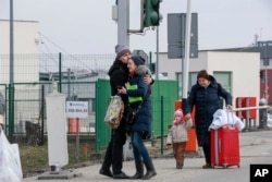 Anggota keluarga berpelukan saat mereka bersatu kembali, setelah melarikan diri dari konflik di Ukraina, di perbatasan Medyka, di Polandia, 27 Februari 2022.(Foto: AP)