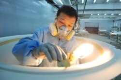 A worker wearing a mask polishes parts for computed tomography (CT) scanners at a factory in Qingdao, Shandong province, China, Feb. 9, 2020. (Credit: China Daily)