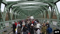 Ukrainian refugees walk a bridge at the buffer zone with the border with Poland in the border crossing of Zosin-Ustyluh, western Ukraine, March 6, 2022.