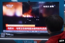 FILE - A resident watches a TV screen showing news about conflict between Russia and Ukraine at a shopping mall in Hangzhou, in China's eastern Zhejiang province, Feb. 25, 2022.