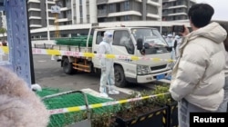 身穿防护服的警察站在运送绿色铁丝围栏的汽车旁。（2022年4月15日）