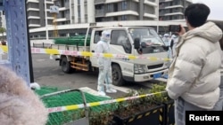 身穿防护服的警察站在运送绿色铁丝围栏的汽车旁。（2022年4月15日）