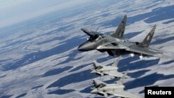 资料照：波兰空军的米格-29战机（上）与意大利空军的台风战机参加北约空中警卫行动在波罗的海上空巡逻。（2015年2月10日）