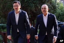 Menteri Luar Negeri Ukraina Dmytro Kuleba, kiri, disambut oleh Menlu Turki Mevlut Cavusoglu menjelang pertemuan tripartit mereka dengan Menteri Luar Negeri Rusia Sergey Lavrov, di Antalya, Turki, Kamis, 10 Maret 2022. (Foto: via AP)