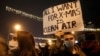 FILE - A high school student holds up a banner protesting dangerous levels of air pollution, in front of the government building in Skopje, North Macedonia, Dec. 20, 2019.