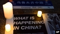 Posters and candles are seen during a gathering at Portsmouth Square in San Francisco, Tuesday, Nov. 29, 2022.