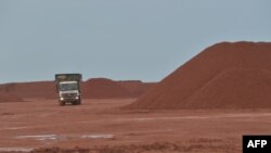 Sebuah truk membawa material di samping tumpukan material bauksit di tambang milik grup Harita di Kendawangan, Kalimantan Barat, 13 Februari 2017. (ADEK BERRY / AFP)