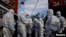 身穿防护服的工作人员进入北京一个被封控的居民区。(2022年11月12日)