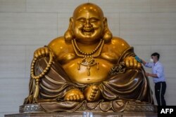 Seorang umat Buddha membersihkan patung Buddha raksasa menjelang perayaan Tahun Baru Imlek di Vihara Bumi Suci Maitreya di Pekanbaru, 11 Januari 2023. (Foto: AFP)
