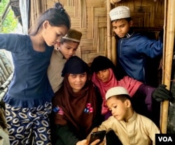 Pengungsi Rohingya Surah Khatoon tampak duduk bersama anak-anaknya ketika berbincang dengan putrinya Sanowara Begum, yang berada di Malaysia, melalui video call, di rumahnya di Cox's Bazar, Bangladesh. (Foto: VOA/Mohammed Rezuwan Khan)