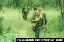 រូបថត​ដែល​ត្រូវ​បាន​ផ្សាយ​ក្នុង​ទំព័រ​ហ្វេប៊ុក​លោក Nate Thayer កាល​ពី​ថ្ងៃ​ទី​៣ ខែ​កញ្ញា ឆ្នាំ​២០១៨​នេះ បង្ហាញ​លោក Nate Thayer ដើរ​ជាមួយ​លោក David McKaige (បុរស​ទី​៣​ដែល​ដើរ​ពី​ក្រោយ​លោក Nate Thayer) និង​ទាហាន​របស់​រណសិរ្សរំដោះជាតិប្រជាជនខ្មែរ​នៅ​ឆ្នាំ​១៩៩០។ ចំណង​ជើងដែល​ត្រូវ​បោះពុម្ព​ជាមួយ​នឹង​រូបថតនេះបាន​សរសេរ​ថា៖ «មួយ​ថ្ងៃ​ទៀត​នៅ​ការិយាល័យ។ ភាគ​ខាង​ជើង​ប្រទេស​កម្ពុជា​ ឆ្នាំ​១៩៨៩»។ (Facebook/Nate Thayer)