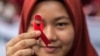 FILE - Seorang pelajar Indonesia memegang pita merah sebagai bagian dari acara kesadaran pada peringatan Hari AIDS Sedunia di Medan, provinsi Sumatera Utara, 2 Desember 2018. -(Albert Ivan Damanik/AFP)