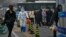 A worker in a protective suit sprays disinfectant as residents stand in line for routine COVID-19 tests in Beijing, Nov. 24, 2022. Citizens have shown increasing frustration with repeated lockdowns and testing for the disease.