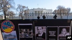 Signs and pictures of those killed, including journalist Brent Renaud, are displayed on a fence during a protest against Russia's invasion of Ukraine in Lafayette Park near the White House, Sunday, March 13, 2022, in Washington. 
