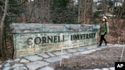 A woman walks by a Cornell University sign on the Ivy League school's campus in Ithaca, New York, Jan. 14, 2022. 