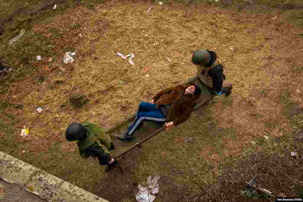 An elderly man is taken by two soldiers to the hospital after living for days in a shelter with limited food and water. Irpin, Ukraine, March 12, 2022. (Yan Boechat/VOA)