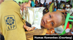 Balita yang digendong ibunya memegang makanan tambahan yang mereka terima di Puskesmas Agats, Kabupaten Asmat, Papua. (FotoL Humas Kemenkes)