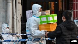 A delivery man delivers an order outside of a locked-down neighborhood after the detection of new cases of COVID-19 in Huangpu district, in Shanghai, on March 15, 2022.
