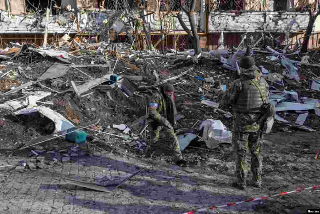Ukrainian servicemen inspect the area outside a residential apartment building after it was hit by Russian shelling in Kyiv, March 15, 2022.
