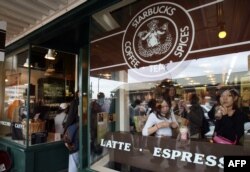 Turis Jepang menikmati kopi di kedai kopi pertama Starbucks di Pike Place Market Seattle, 30 September 2006. Gerai ini berdiri sejak 1971. (AFP PHOTO/GABRIEL BOUYS)