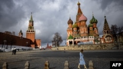 FILE - A woman walks under cloudy skies near the Kremlin and St. Basil's Cathedral in central Moscow, Russia, Feb. 22, 2022. 