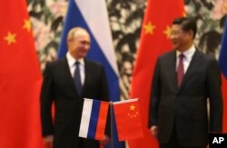 Bendera nasional Rusia dan China berdiri di depan sebagai Presiden Rusia Vladimir Putin, kiri, dan timpalannya dari China Xi Jinping. (Foto: AP)