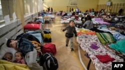 Anak-anak bermain di tempat penampungan sementara untuk pengungsi Ukraina di sebuah sekolah di Przemysl, dekat perbatasan Ukraina-Polandia pada 14 Maret 2022. (Foto: AFP)