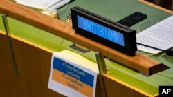 FILE - A sign reading "#TodayWeAreAllUKRAINE" hangs from the desk of the Swiss delegation, Feb. 28, 2022, at United Nations Headquarters.