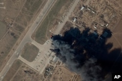 资料照片：Planet Labs PBC提供的卫星图片显示，在乌克兰军队据信发动空袭，摧毁了俄军直升机和坦克的一天后，赫尔松国际机场和空军基地冒出的烟火。(2022年3月15日)