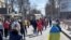 Demonstrators, some displaying Ukrainian flags, chant 'go home' while Russian military vehicles reverse course on the road, at a pro-Ukraine rally amid Russia's invasion, in Kherson, March 20, 2022 in this still image from video obtained by Reuters. 