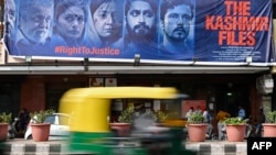Sebuah bajaj tampak melewati poster film Bollywood 'The Kashmir Files' yang terpasang di luar bioskop di New Delhi, India, pada 21 Maret 2022. (Foto: AFP/Sajjad Hussain)