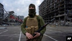 Ukrajinski vojnik stoji u centru Kijeva ispred tržnog centra uništenog u napada 21. marta 2022.