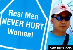 Seorang pria memegang plakat untuk membela perempuan. Komnas Perempuan mendorong orang untuk menghentikan kekerasan dalam rumah tangga (KDRT), masalah yang lazim dan sering diabaikan di masyarakat. (Foto: AFP/Adek Berry)