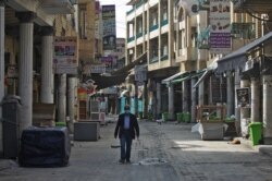 Seorang pria Irak berjalan melewati toko-toko yang tutup di Baghdad, di tengah pemberlakuan pembatasan di tengah pandemi COVID-19, 19 Februari 2021. (Foto: AHMAD AL-RUBAYE / AFP)