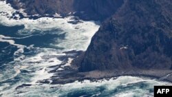 This aerial view from a Jiji Press helicopter shows another helicopter flying near the coast of the northern Japanese island of Hokkaido on April 29, 2022, where a distress signal was made by the sightseeing boat Kazu 1 on April 23. 